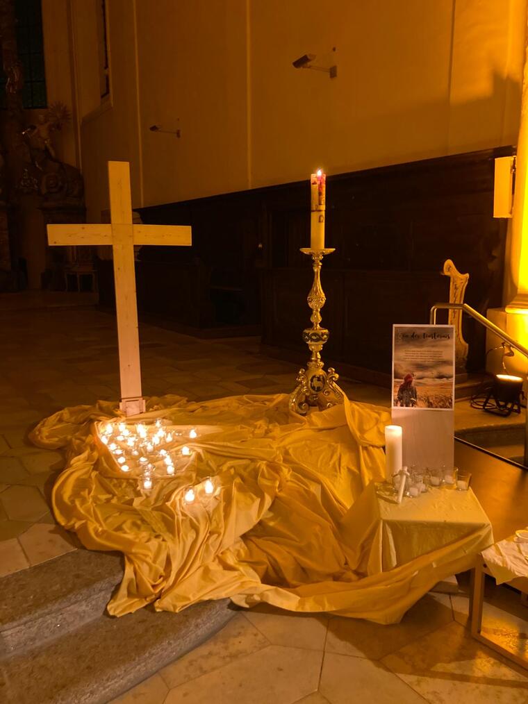 Holzkreuz mit Kerzen im Vordergrund